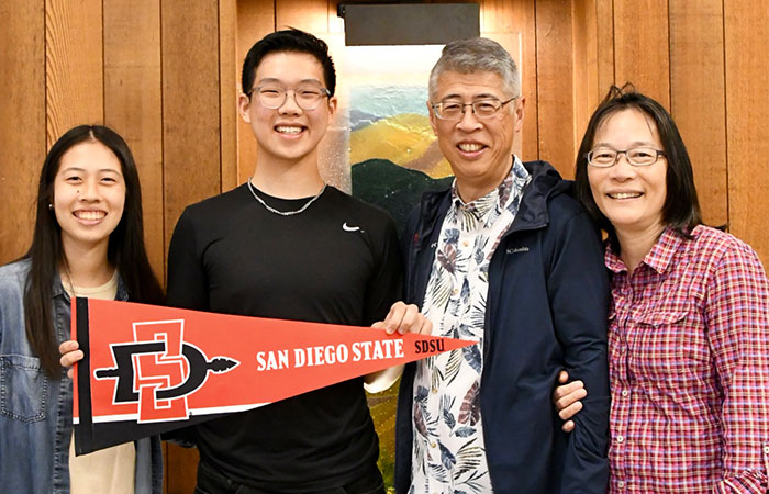 a family of four with young male holding a San Diego State pendant