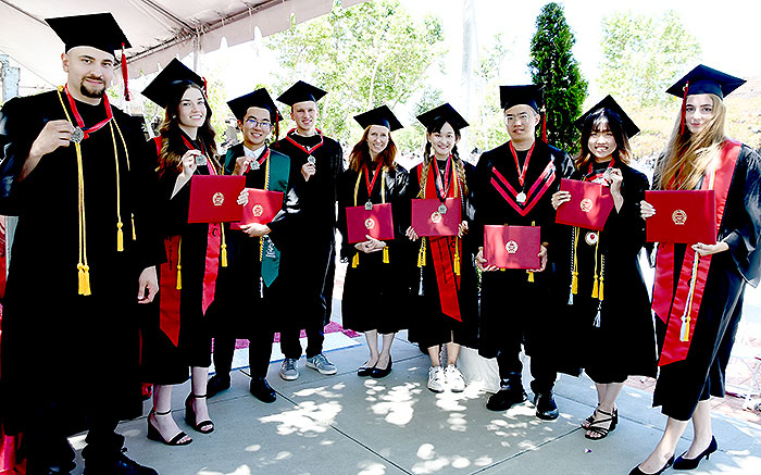 9 graduates holding medals