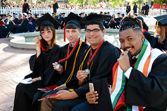 Four graduates holding medals