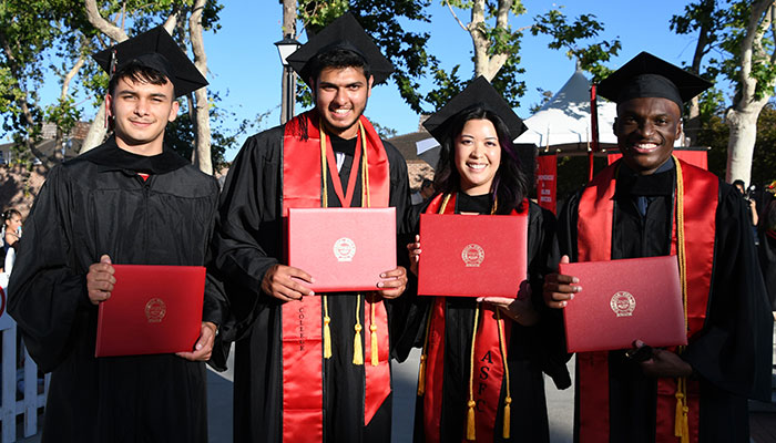 four graduates in cap and gown