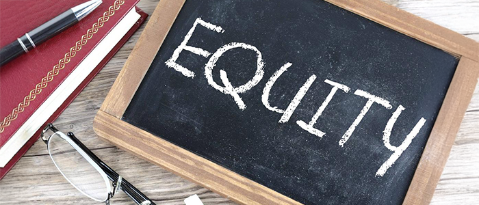 Image of "Equity" on a chalkboard with academic materials surrounding it