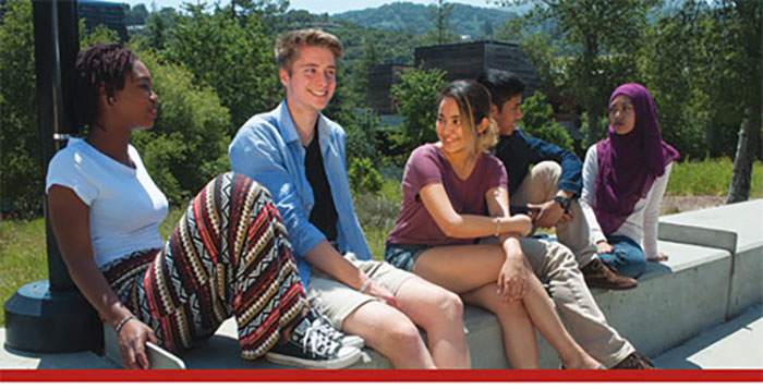 4 students sitting on a cement bench